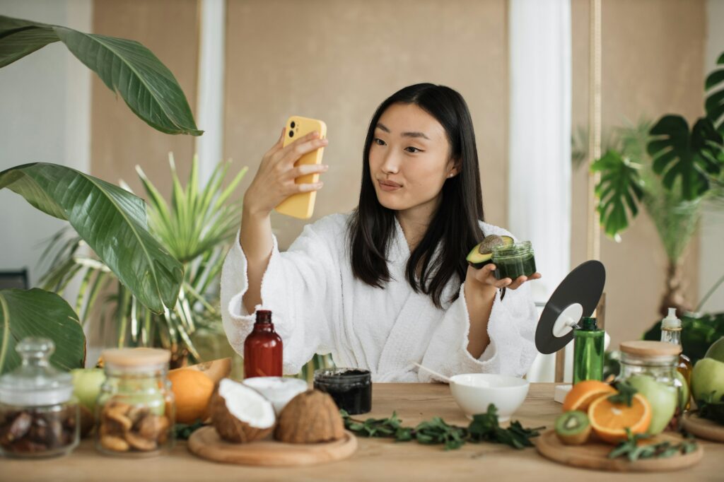Asian brunette shoulder length hair female social media influencer holding glass jar with cream