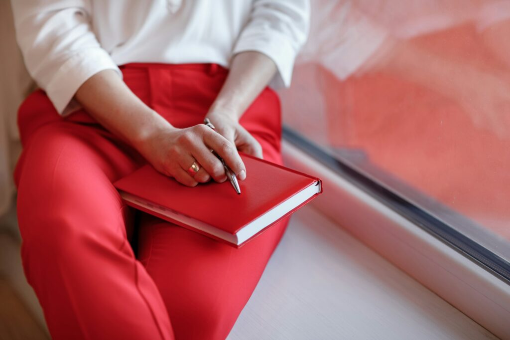 cropped photo of young European businesswoman with notebook is sitting by the window. planning