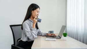 woman is showing credit card and using laptop for online shopping to purchasing product on website