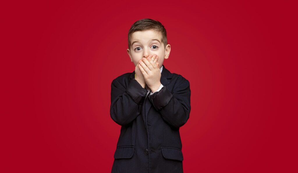 Shocked schoolboy covering mouth