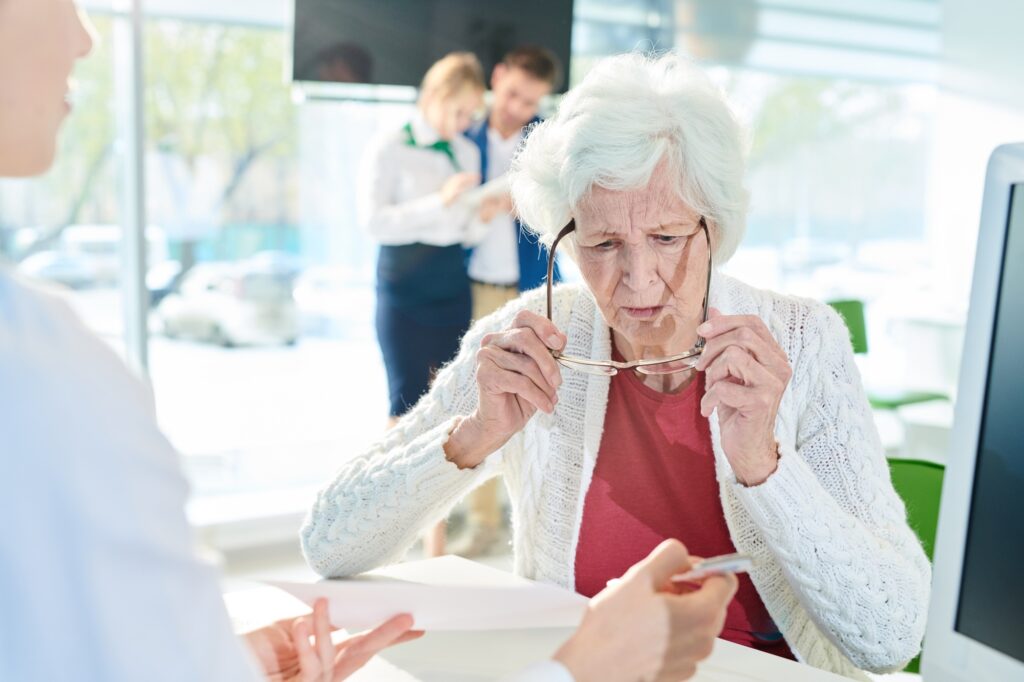 Confused senior lady examining document in bank office